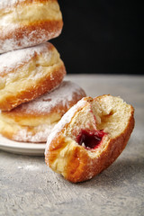 A stack of three sufganiyot donuts with jelly on black background