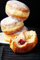 A stack of three sufganiyot donuts with jelly on black background