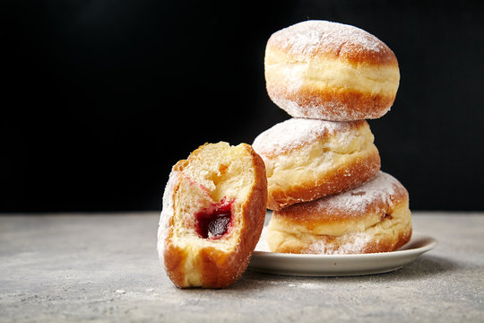 A stack of three sufganiyot donuts with jelly on black background