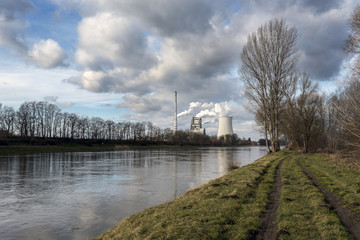 Fototapeta premium the factory launches smoke into the air on the shore of a beautiful river in Bohemia