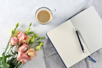 Open notebook with flowers on white marble