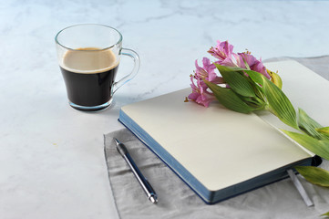 Open notebook with Lily flowers and black coffee