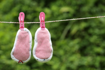 Baby gloves hanging on the clothesline with green Nature background