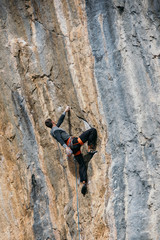 Fototapeta premium Man climbs a yellow rock with a rope, lead