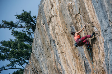 Woman climbs a yellow rock with a rope, lead, side view