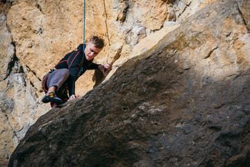 Man climbs yellow rock top rope, side view