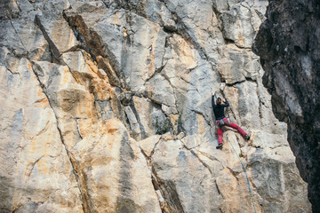 Woman climbs a yellow rock with a rope, lead, side view