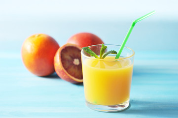 orange juice in glass with mint and a straw