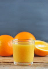 glass with fresh orange juice on the background of whole oranges
