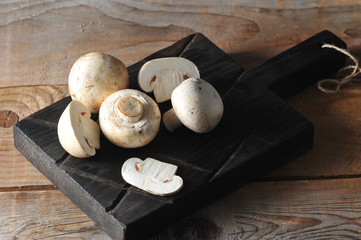 Fresh white mushrooms champignon on rustic wooden background