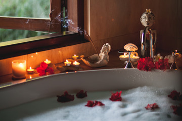 Large Filled Bath with Foam and Flowers. Romantic Atmosphere, Burning Scented Candles and Aromasticks