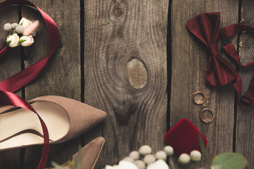 flat lay with ribbon, corsage, bridal and grooms shoes on wooden tabletop