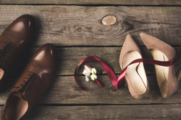 flat lay with bridal  shoes, bow tie, wedding rings on wooden surface