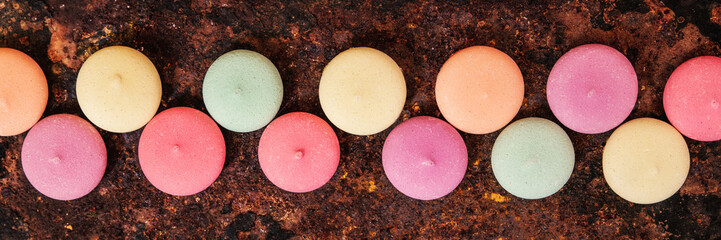 Fototapety  Panorama, makaroniki, ciasteczka lub biszkopty kolorowe w rzędzie, tło rdza