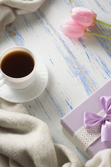 Cup with Coffee, Scarf, Gift, Tulips on the White Wooden Table. Concept of Spring