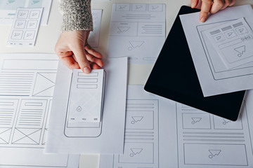 Web designer creating mobile responsive website. Website wireframe sketches on white table