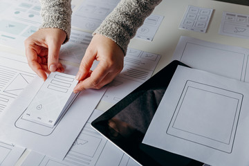 Web designer creating mobile responsive website. Website wireframe sketches on white table