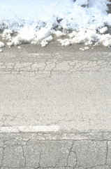 Urban road with damaged asphaltand a pile of snow, vertical from above