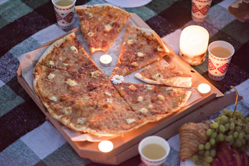 Romantic dinner in the nature by candlelight with pizza. Two lovers eat pizza. Romantic date for two.