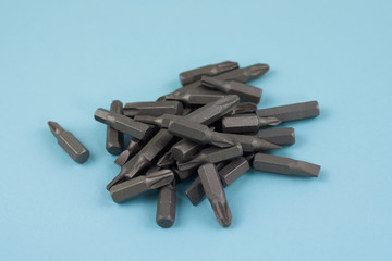 Heap of metal bits for screwdriver in form of triangle on blue background