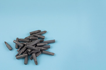 Heap of metal bits for screwdriver in form of triangle on blue background with copy space
