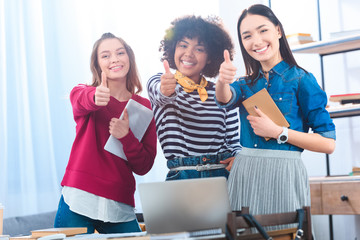 portrait of smiling multiethnic students showing thumbs up