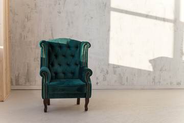 Green armchair on white wall background near window. Loft style