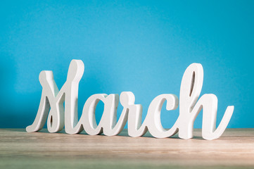 March - 1st month of spring. Wooden carved word at light blue background. Card for Mothers day, 8 March, Easter