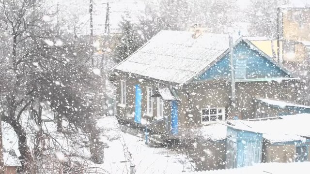 Blizzard, snow, large flakes falling on an old house in the province. Blurred video.