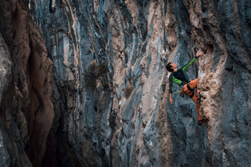 Men climbs a rock, 7c pitch with a rope, lead. Chitdibi, Turkey