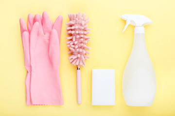 concept cleaning, on a yellow background pink gloves c soft dust brush, melamine sponge and spray for glasses