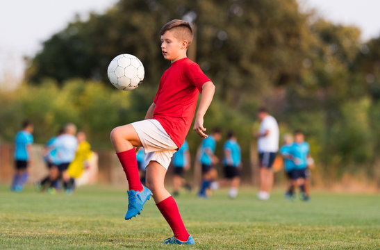 Boy kicking football on the sports field