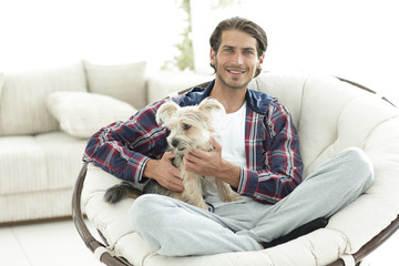 handsome guy with a dog sitting in a large armchair.