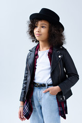 stylish little child in leather jacket looking away isolated on grey