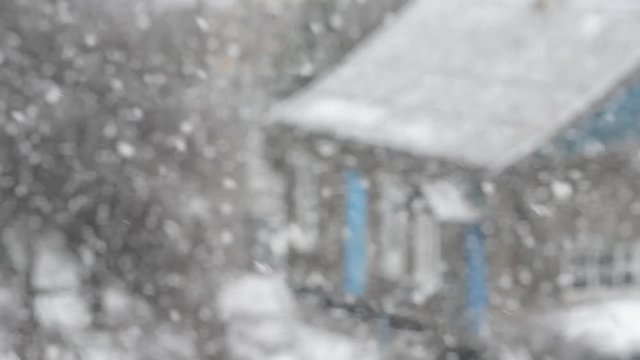Blizzard, snow, large flakes falling on an old house in the province. Blurred video.