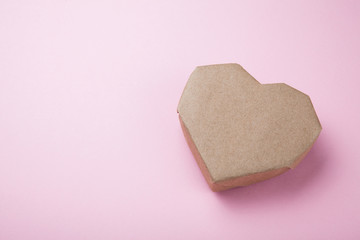Paper heart made from recycled paper on a pink background, empty space for text.
