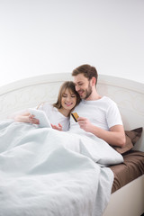 Fototapeta premium Smiling woman using digital tablet with her boyfriend holding credit card in cozy bedroom