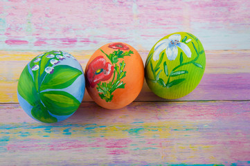 Three easter eggs decorated with flower drawings laying on table