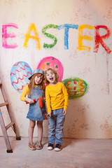 a boy and a girl with a roller in jeans and a white T-shirt, a brush and a bucket paint the wall in red.