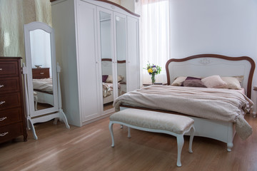Fototapeta na wymiar Interior of cozy bedroom with closet, bed and mirrors in modern design
