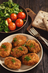 Fried meat cutlets, tomatoes and salad on wooden background.