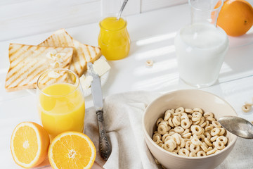 Delicious Healthy breakfast.  Whole Grain Cereal rings, milk, honey and orange juice on the white table. Cheerios whole grain cereals with milk. Healthy lifestyle.