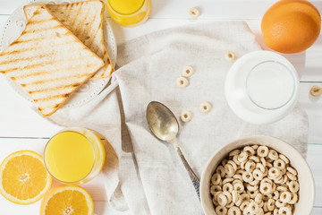 Delicious Healthy breakfast.  Whole Grain Cereal rings, milk, honey and orange juice on the white table. Cheerios whole grain cereals with milk. Healthy lifestyle.