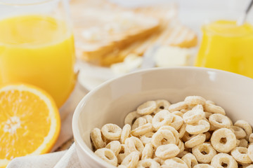 Delicious Healthy breakfast.  Whole Grain Cereal rings, milk, honey and orange juice on the white table. Cheerios whole grain cereals with milk. Healthy lifestyle.
