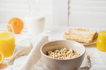 Delicious Healthy breakfast.  Whole Grain Cereal rings, milk, honey and orange juice on the white table. Cheerios whole grain cereals with milk. Healthy lifestyle.