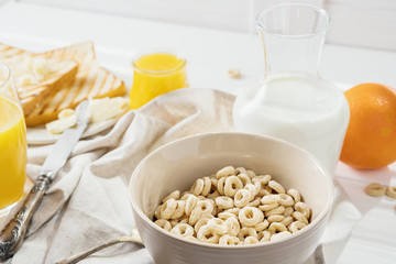 Delicious Healthy breakfast.  Whole Grain Cereal rings, milk, honey and orange juice on the white table. Cheerios whole grain cereals with milk. Healthy lifestyle.