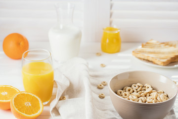 Delicious Healthy breakfast.  Whole Grain Cereal rings, milk, honey and orange juice on the white table. Cheerios whole grain cereals with milk. Healthy lifestyle.