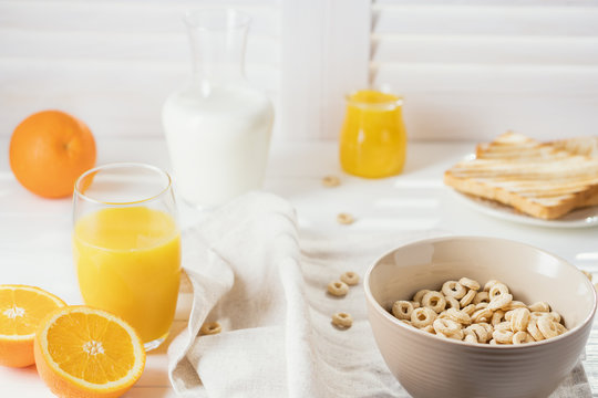 Delicious Healthy breakfast.  Whole Grain Cereal rings, milk, honey and orange juice on the white table. Cheerios whole grain cereals with milk. Healthy lifestyle.