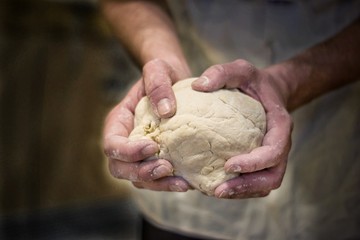 Hands rumple dough in kitchen.Defocus in the background.
