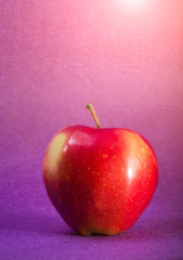 Red apple closeup on violet background. Juicy fruit. Healthy food. Vitamins.
